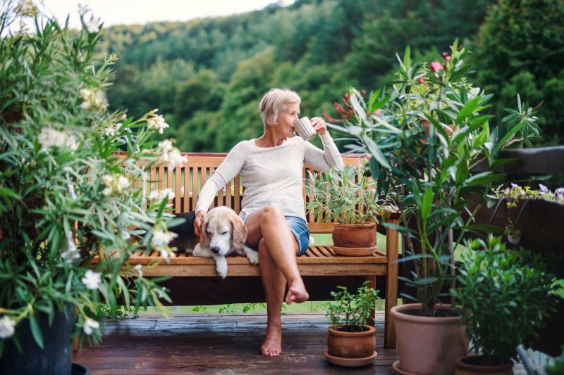 An older woman sitting on a porch swing on a nice day.